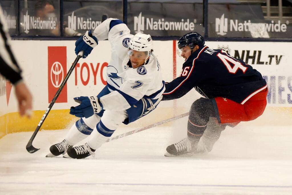 Mathieu Joseph of the Tampa Bay Lightning and Dean Kukan of the Columbus Blue Jackets chase after a loose puck