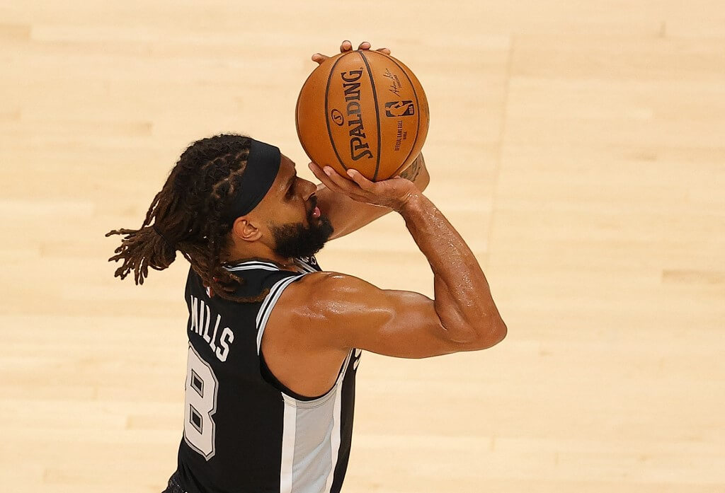 Patty Mills of the San Antonio Spurs shoots a three-point basket and draws a foul from Solomon Hill of the Atlanta Hawks