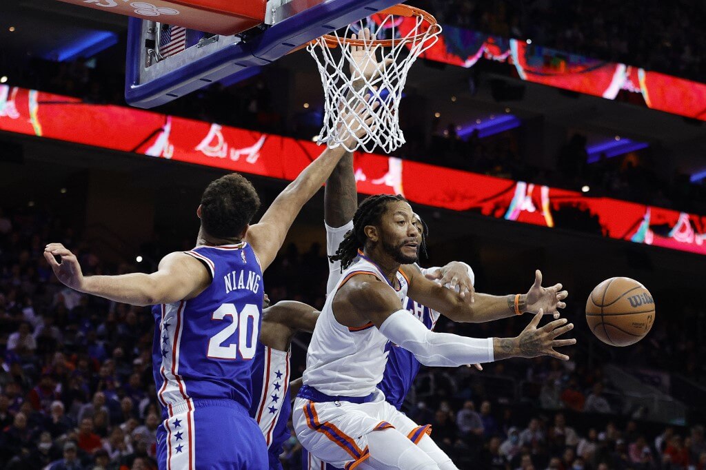 Derrick Rose of the New York Knicks passes between Georges Niang and Andre Drummond of the Philadelphia 76ers
