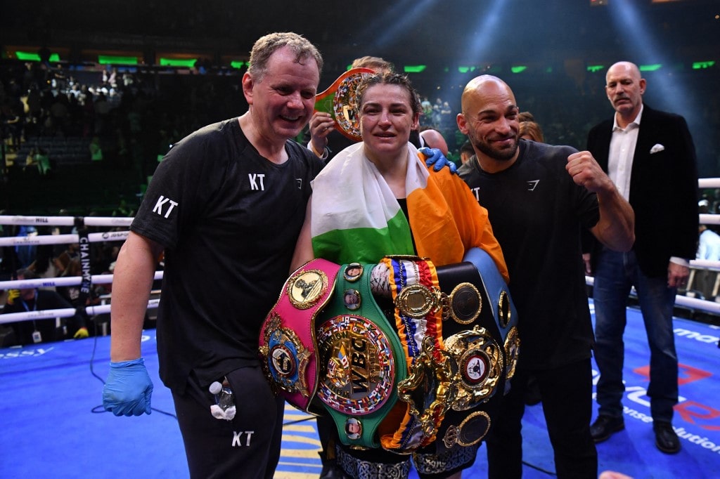 Irish boxer Katie Taylor (C) celebrates, alongside manager Brian Peters (L) and coach Ross Enamait (R) after defeating Puerto Rican boxer Amanda Serrano 