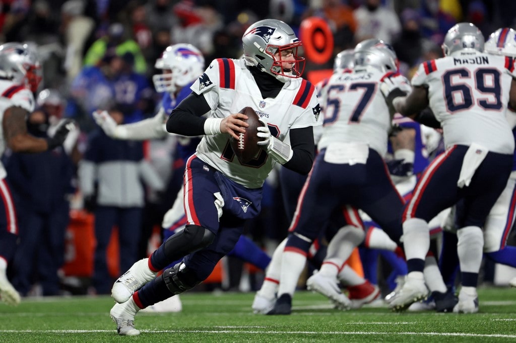 Mac Jones #10 of the New England Patriots looks to throw a pass against the Buffalo Bills during the fourth quarter in the AFC Wild Card playoff game 