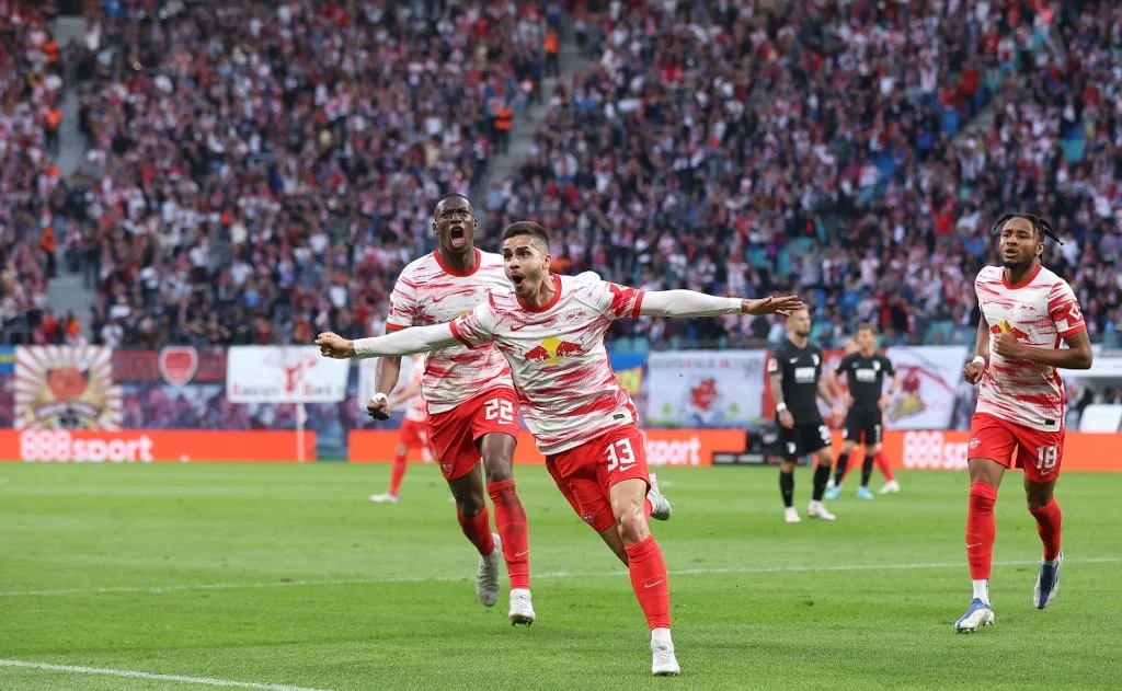 Leipzig's Portugese forward Andre Silva (C) celebrates scoring the opening goal with Leipzig's French defender Nordi Mukiele (L) and Leipzig's French midfielder Christopher Nkunku during the German first division Bundesliga football match