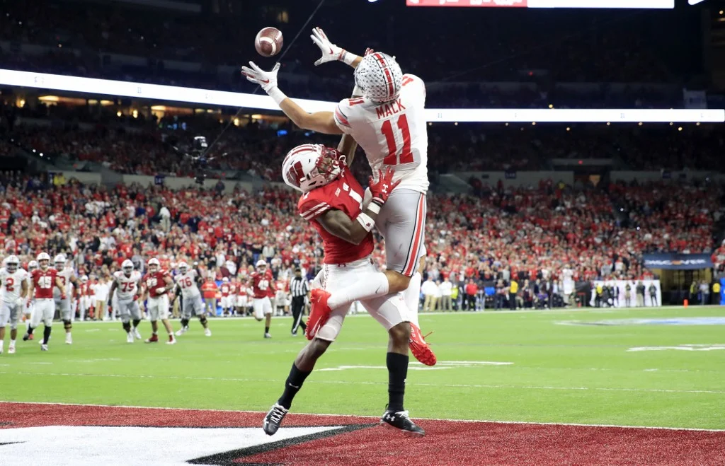 Austin Mack #11 of the Ohio State Buckeyes reaches to catch a pass while defended by Faion Hicks #1 of the Wisconsin badgers during the BIG Ten Football Championship at Lucas Oil Stadium on December 07, 2019