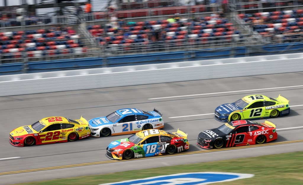Joey Logano, driver of the #22 Shell Pennzoil Ford, and Kyle Busch, driver of the #18 M&M's Toyota, lead a pack of cars
