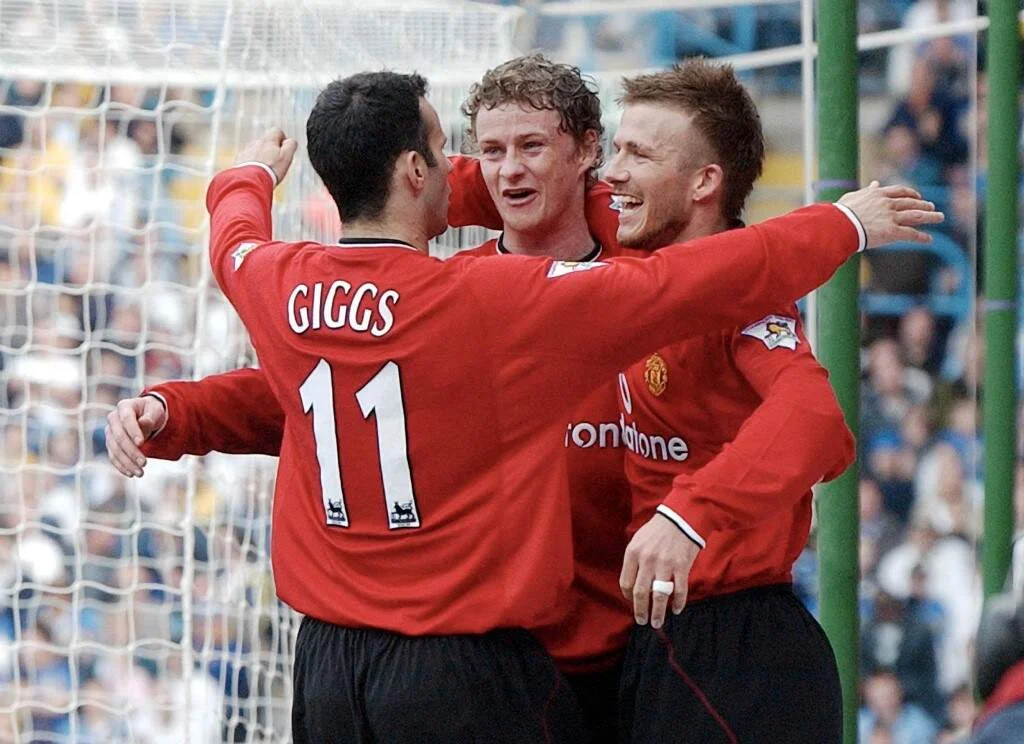 Manchester United player Ryan Giggs (L) hugs teammates Ole Gunnar Solskjaer (C) and David Beckham