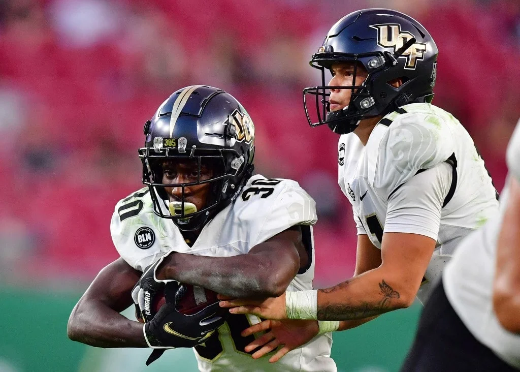 Dillon Gabriel #11 hands the ball off to Greg McCrae #30 of the UCF Knights