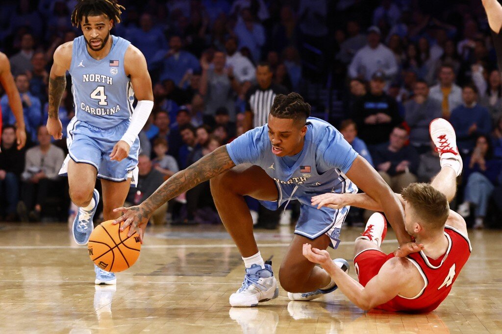 Armando Bacot #5 of the North Carolina Tar Heels fights off Sean McNeil #4 of the Ohio State Buckeyes as he chases down a loose ball
