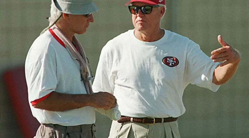 George Seifert (L) listens to 49ers consultant Bill Walsh 